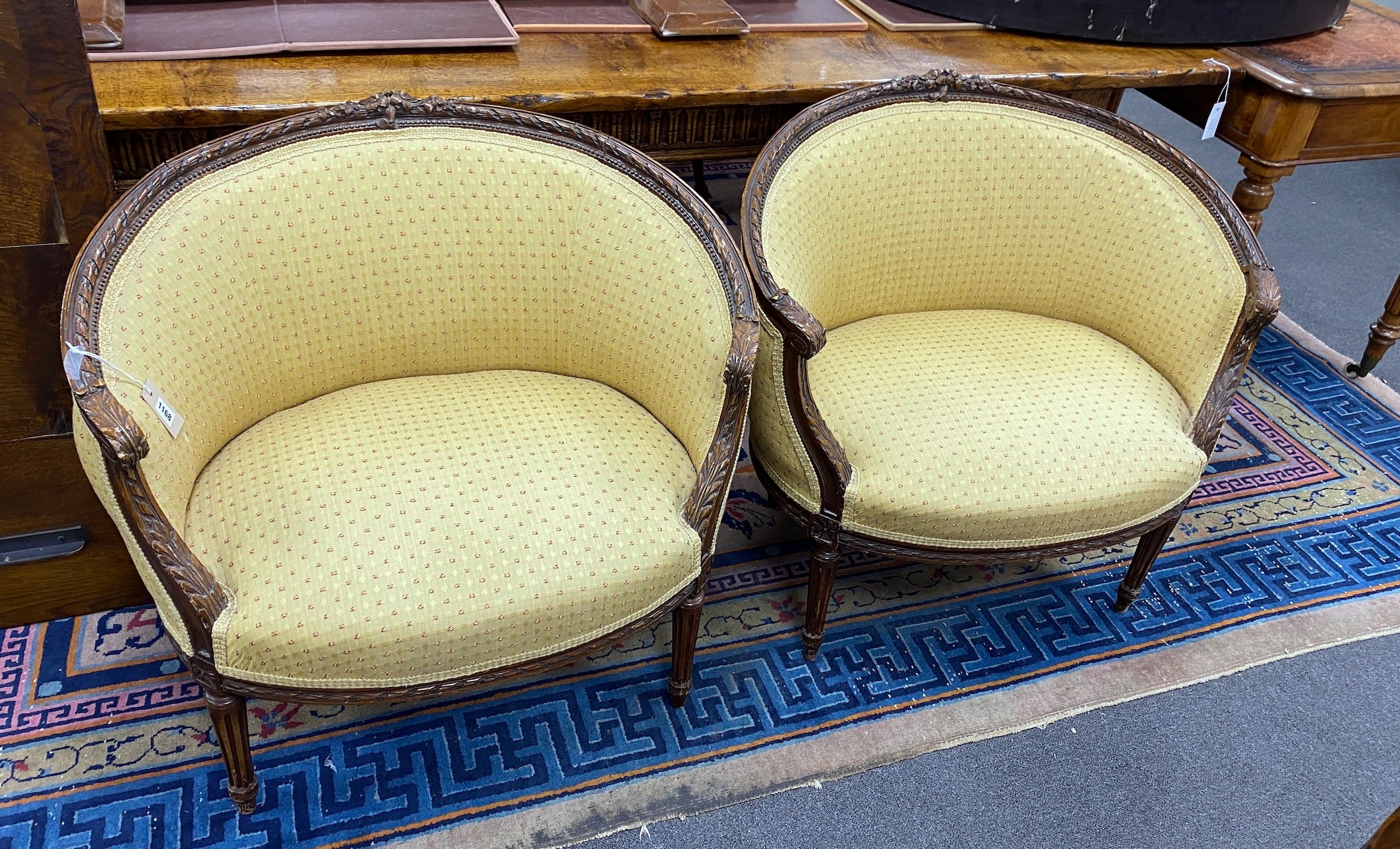 A pair of Louis XVI style carved beech upholstered tub framed chairs, width 82cm, depth 50cm, height 77cm